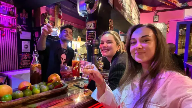 Friends raising their cocktails at a colourful bar